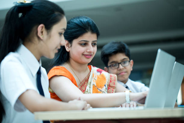 teacher holding digital tablet while teaching students in classroom