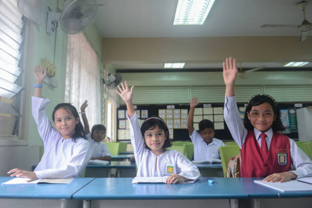 school children raised hand to answer questions in the classroom at school